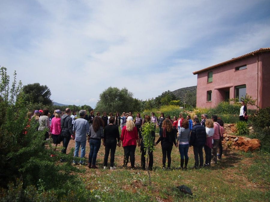 group of tourists holding hands in circle and listening to a woman at holistic workshop at Korogonas Ark outside